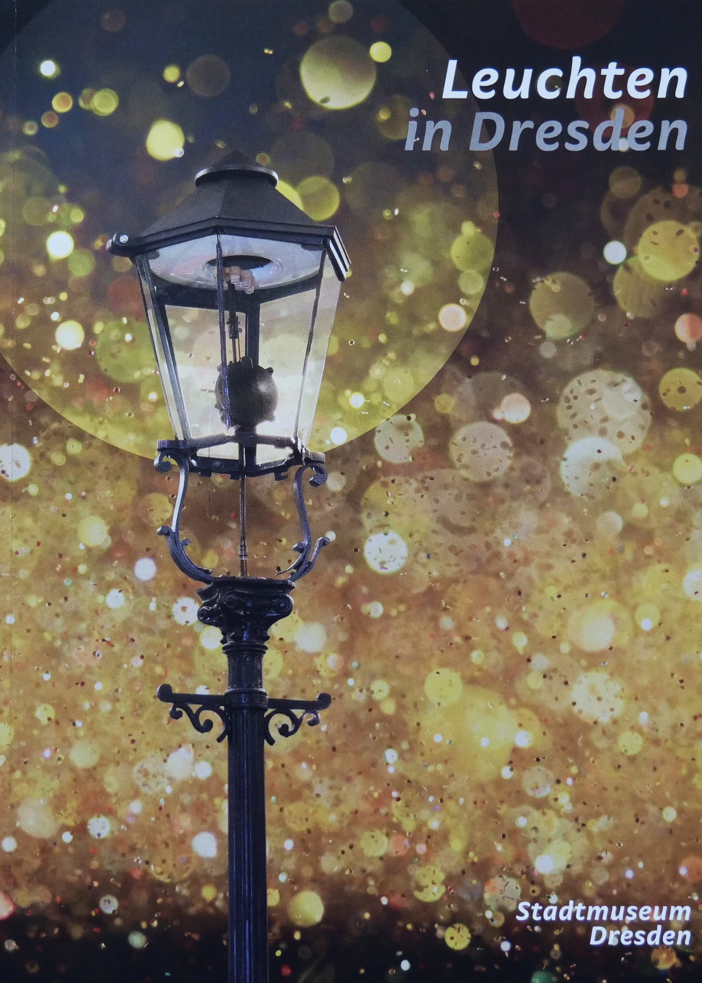 KI generiert: Das Bild zeigt eine historische Straßenlaterne vor einem Hintergrund aus goldenen Lichtern. Der Text verweist auf eine Ausstellung im Stadtmuseum Dresden mit dem Titel "Leuchten in Dresden".