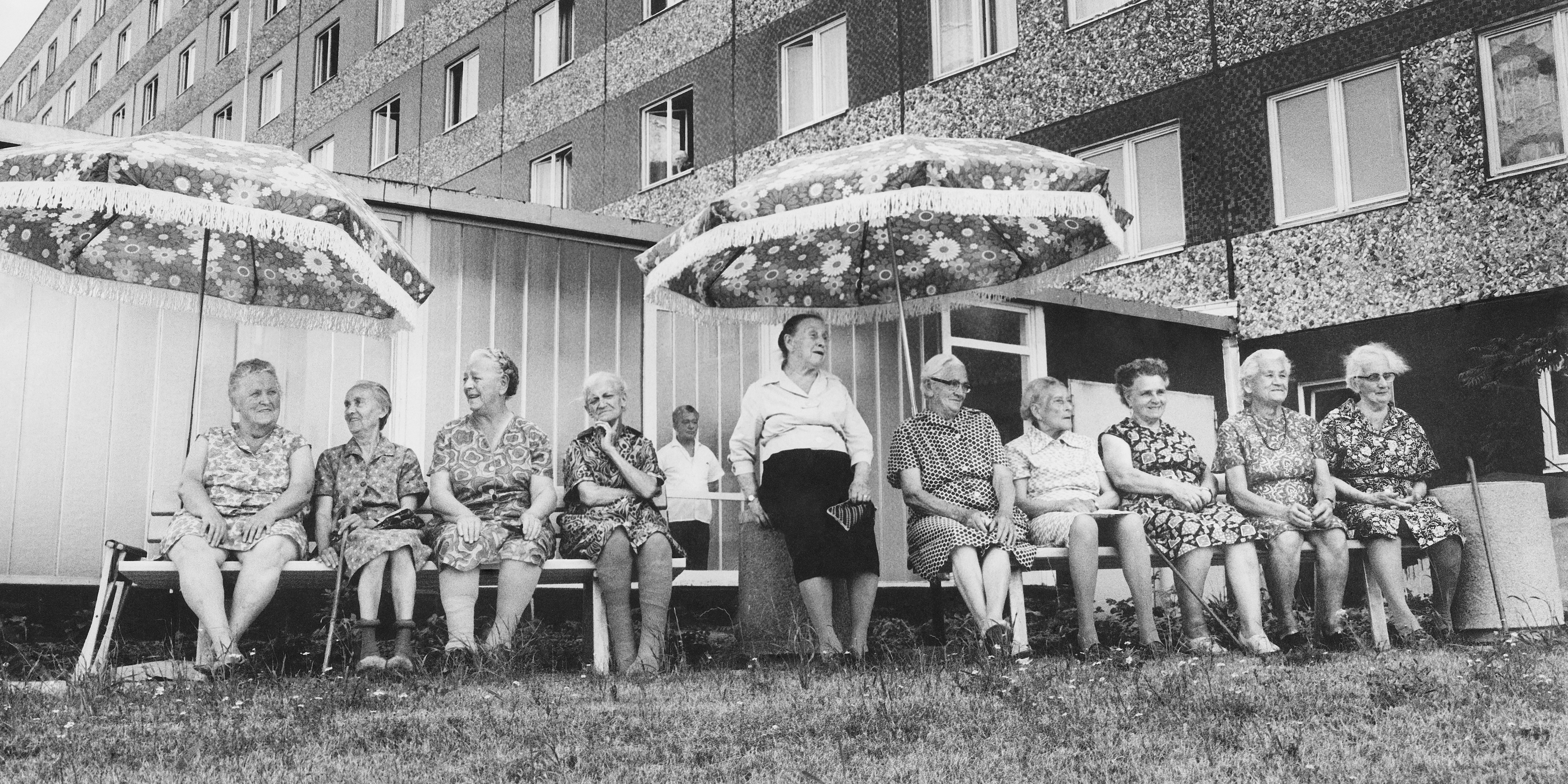 KI generiert: Das Bild zeigt eine Baustelle in einer städtischen Umgebung mit mehreren Hochhäusern im Hintergrund. Ein großes Wandgemälde auf einem der Gebäude sticht hervor, und im Vordergrund sind lose Materialien und unvollständige Straßen zu sehen.