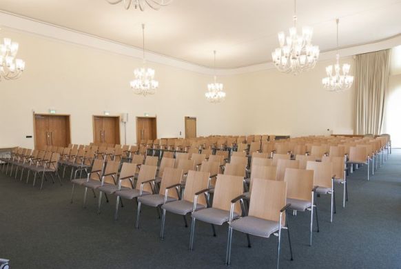 Blick in den Festsaal mit leeren Stuhlreihen.